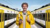 Ein Mann in gelber Kleidung steht mit seinem Handy am Bahnhof. Links und rechts von ihm steht jeweils ein bwegt-Zug.
