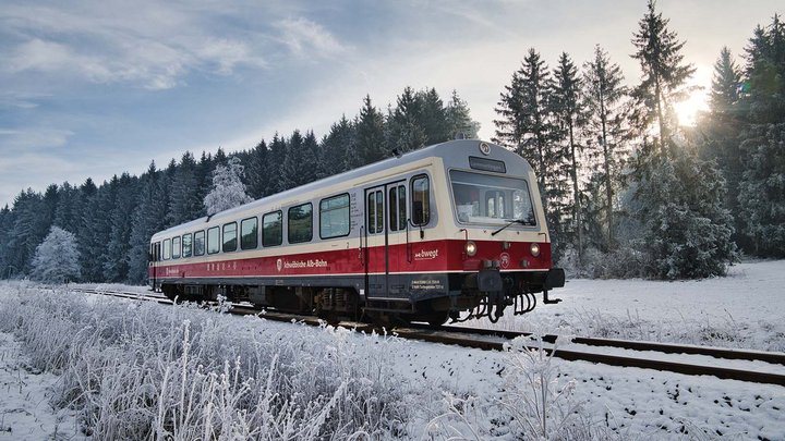 Historische Bahn in weiß und rot fährt durch eine Winterlandschaft.