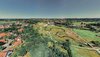 Blick über eine grüne Landschaft mit Häusern und Baumgruppen.