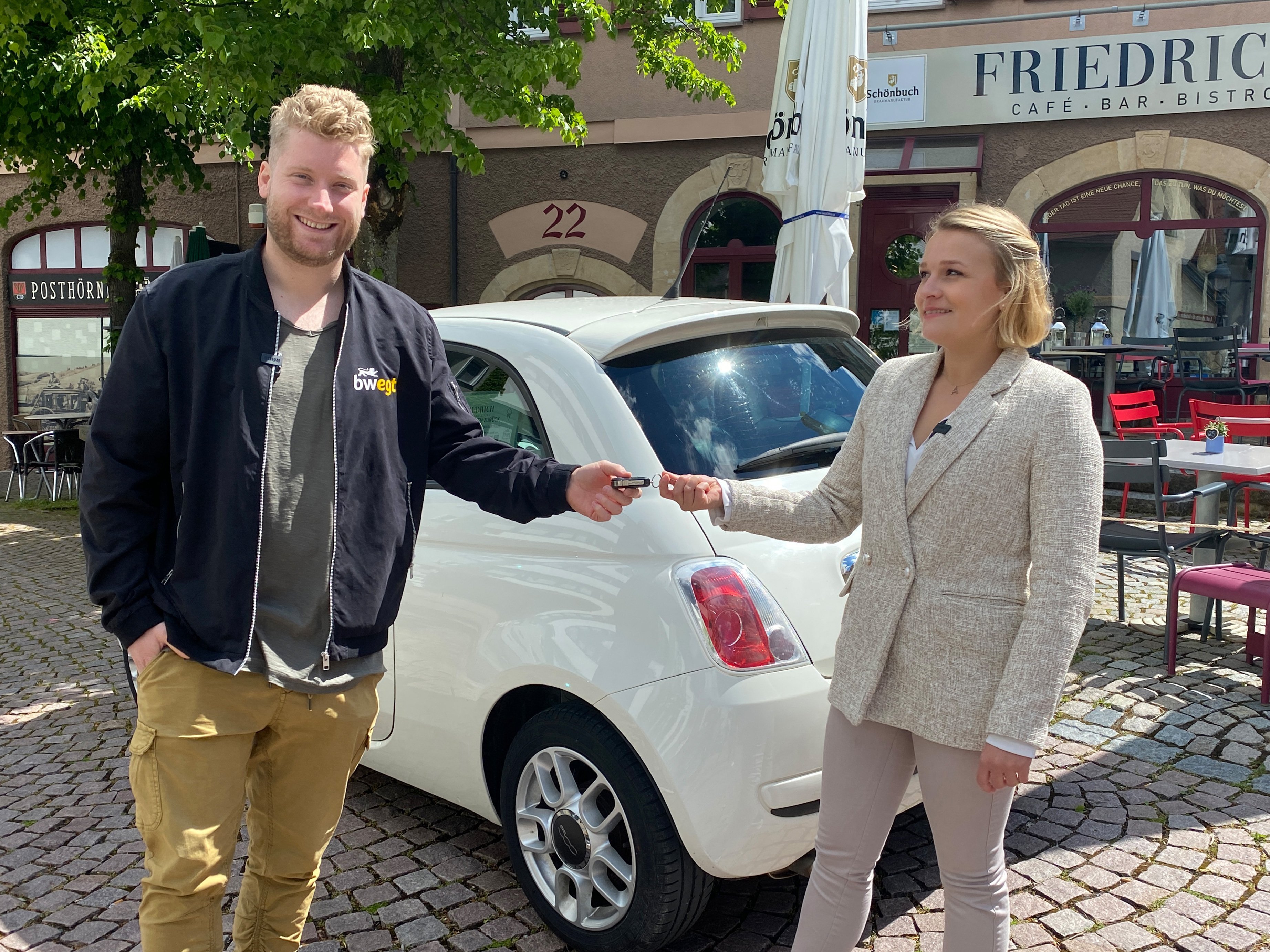 Frau übergibt ihren Autoschlüssel einem lächelnden Mann.