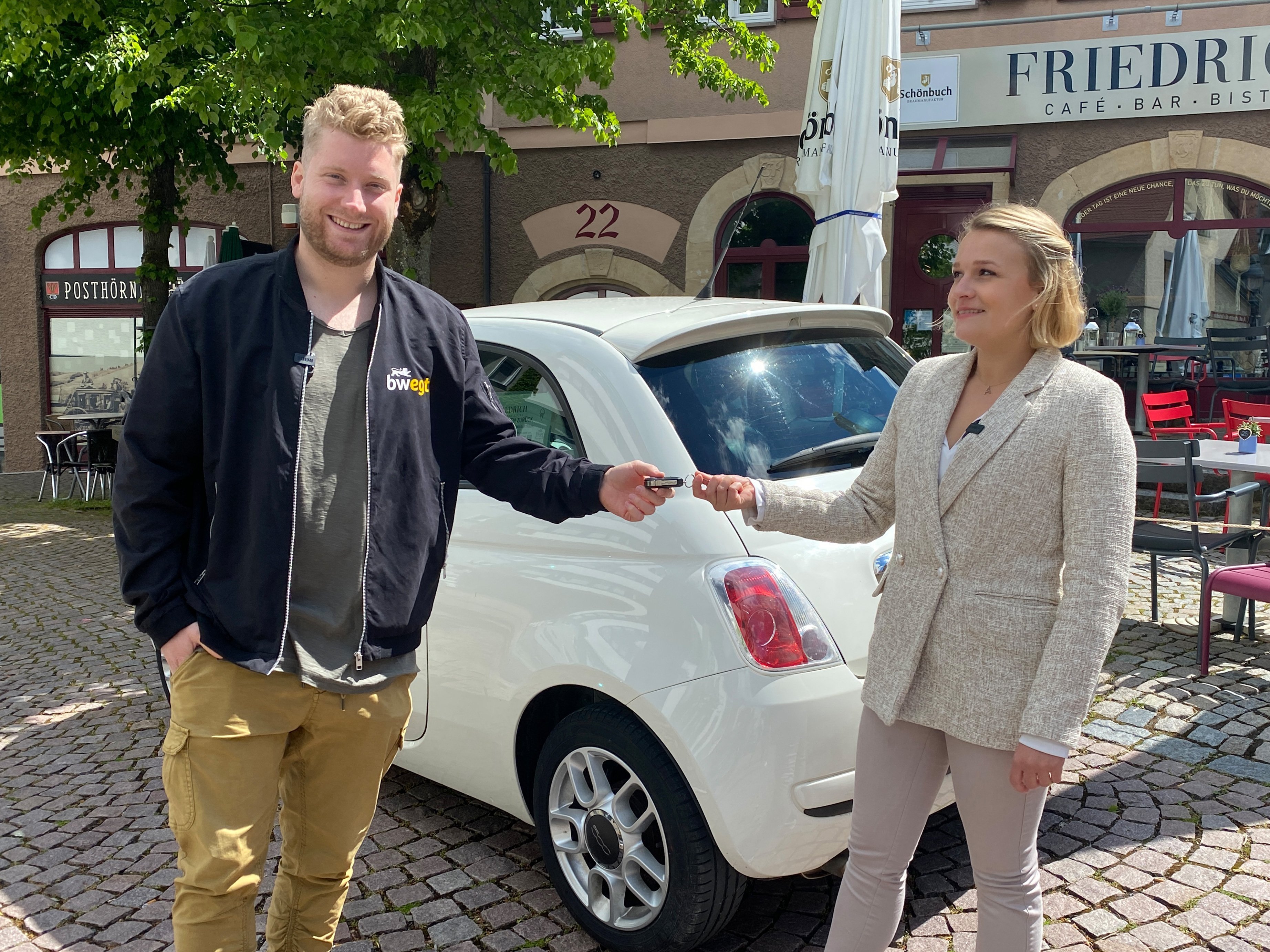 Frau übergibt ihren Autoschlüssel an einen lächelnden Mann.