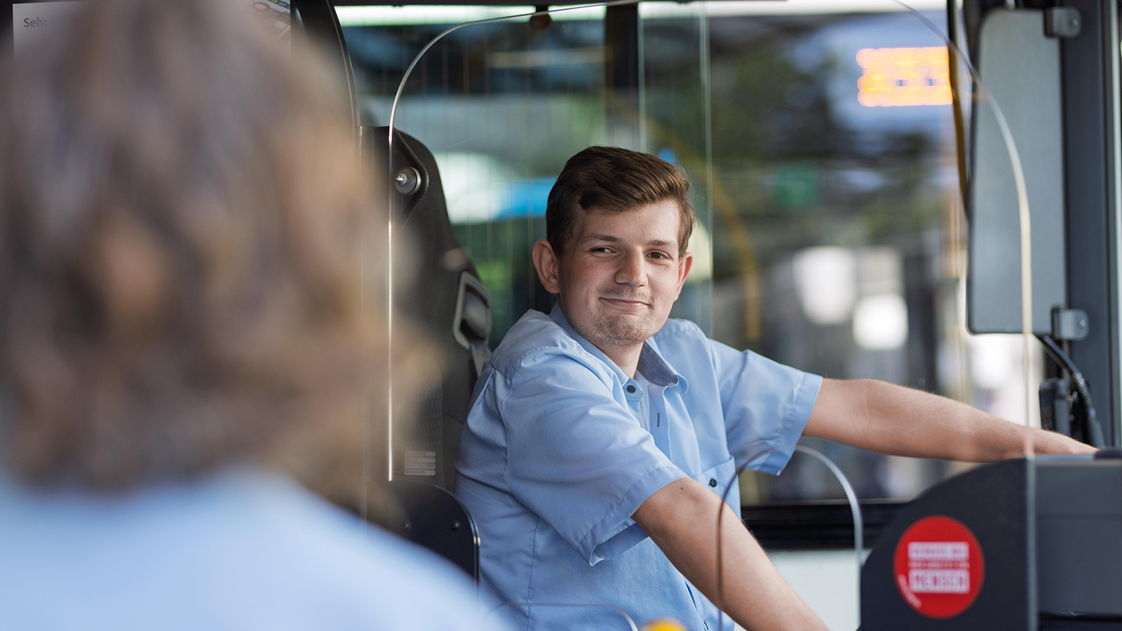 Ein Busfahrer begrüßt eine Frau beim Einstieg