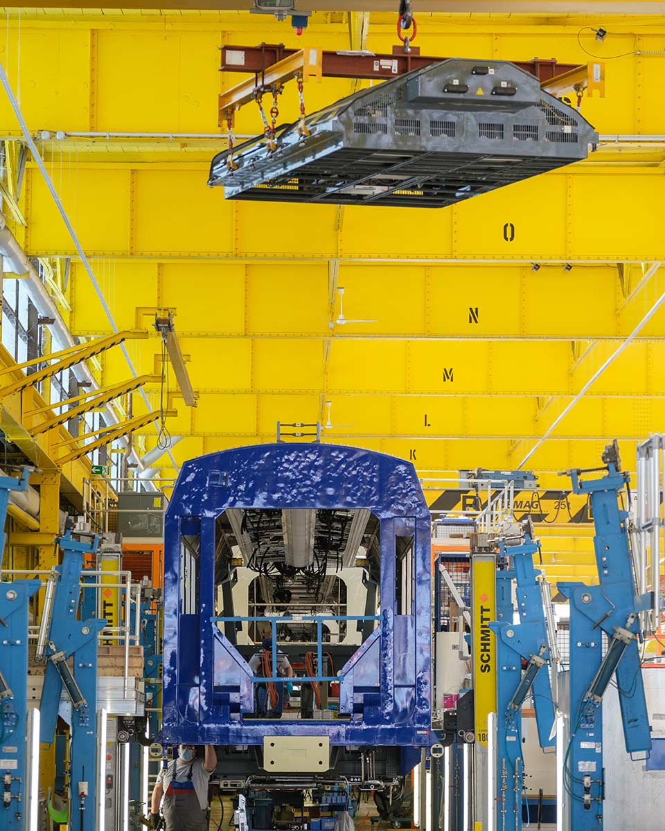 In einer Halle wird die Brennstoffzelle mit einem Kran auf dem Zug platziert.Die Brennstoffzelle ist das Herzstück des Coradia iLint des Herstellers Alstom: Sie wandelt Wasserstoff in elektrische Energie um. Bildquelle: Alstom/Christoph Busse