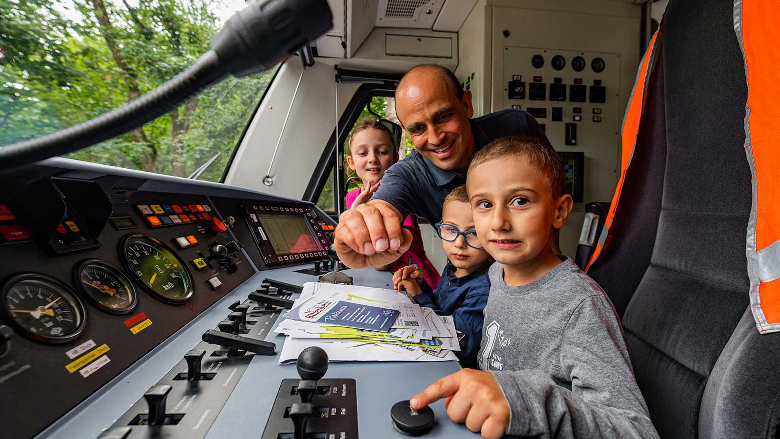 Drei Kinder sitzen mit einem Mann im Führerstand des Freizeitexpresses.