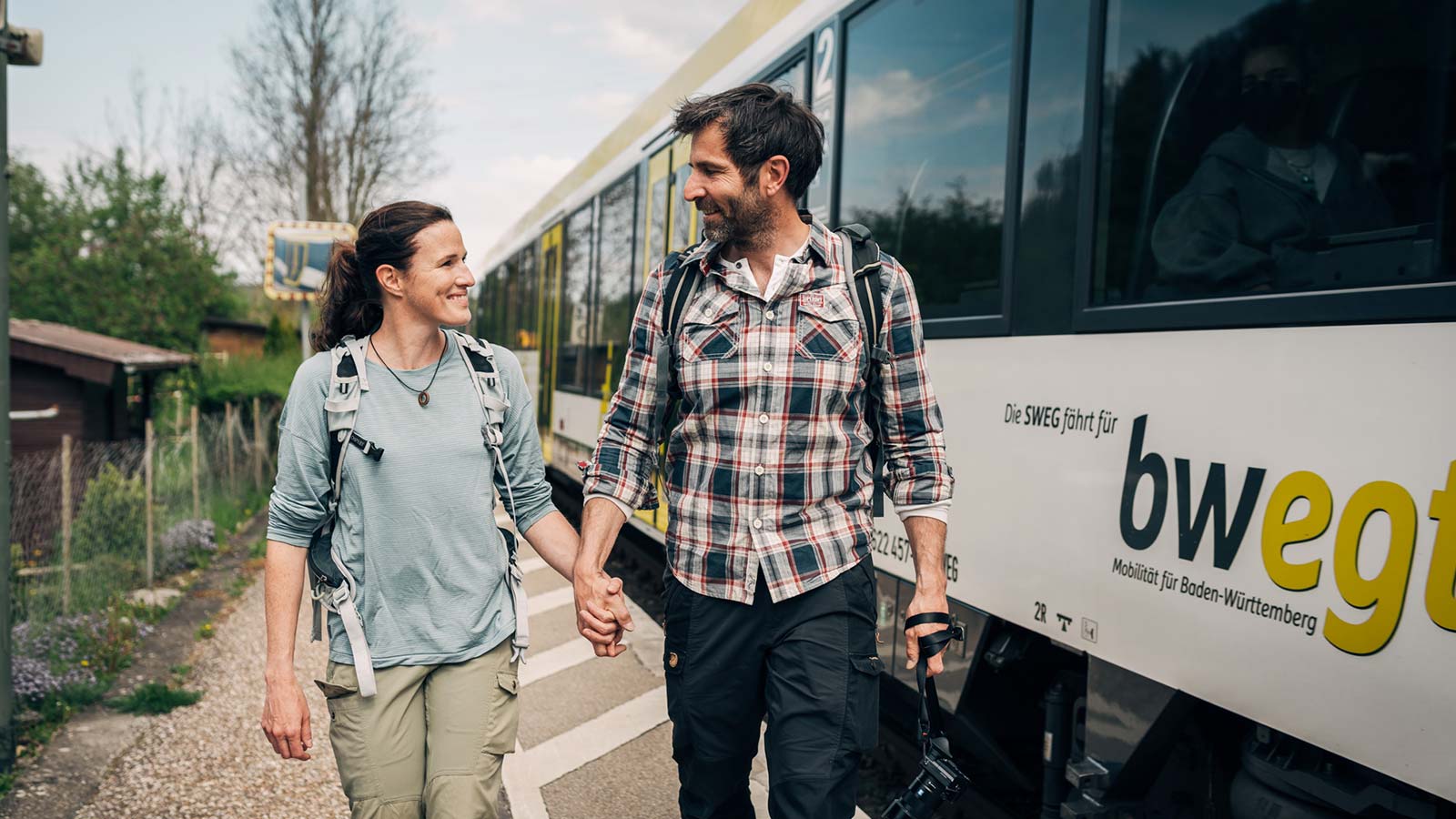 Mann und Frau gehen Hand in Hand an einem Zug vorbei.