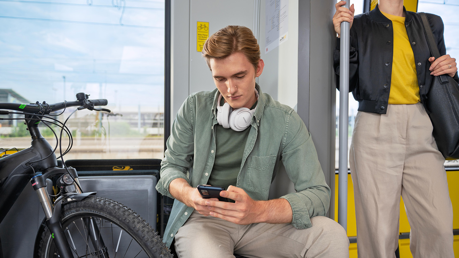 Ein junger Mann schaut während der Bahnfahrt auf sein Smartphone